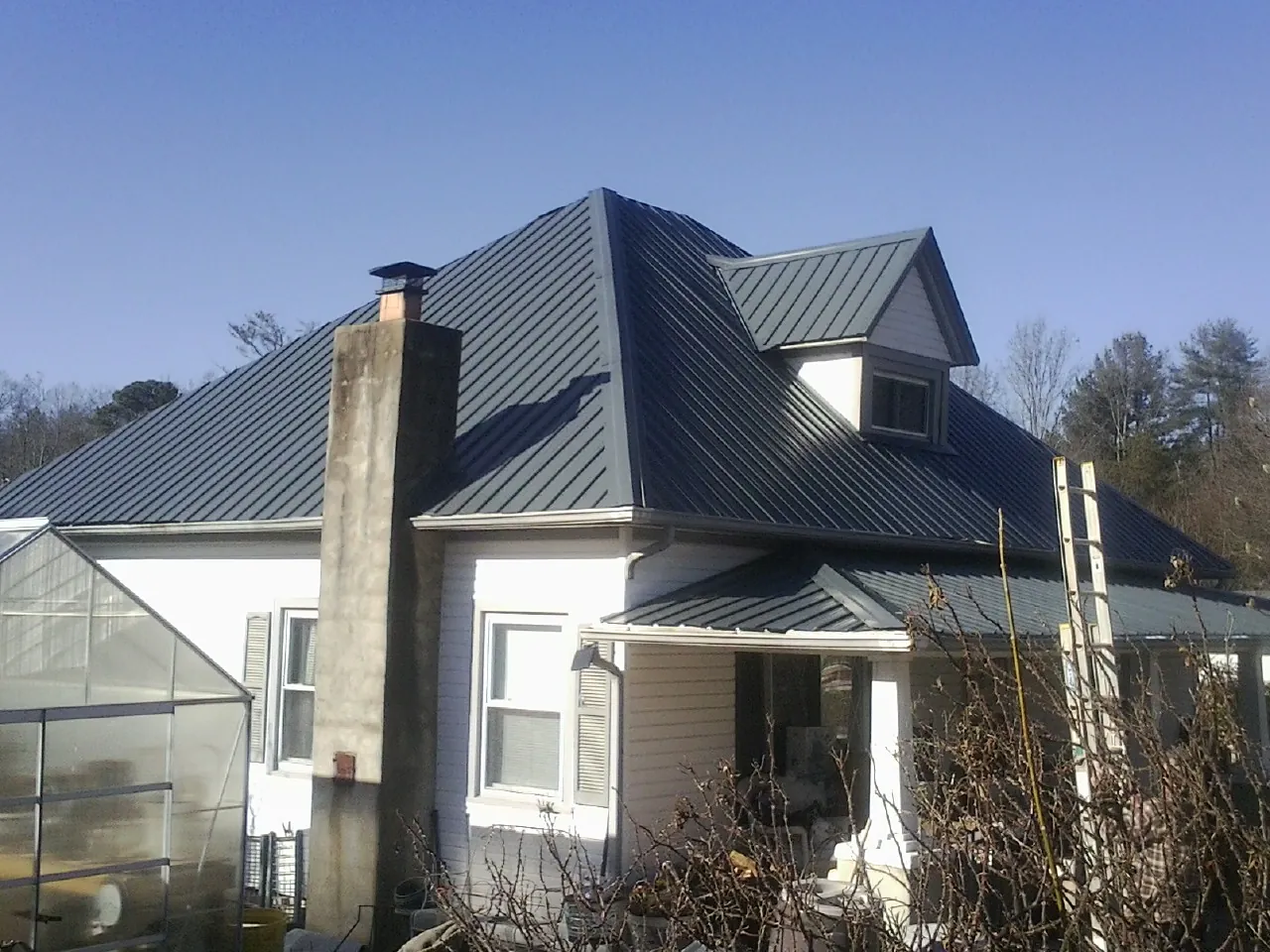 Dark blue standing seam metal roof on a white farmhouse with dormer — Slate & Tile Roof Repair by Roofing Brothers in Mary D