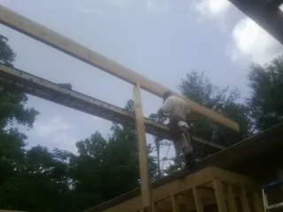 Carpenter setting a ridge beam over a new addition frame — Ice Dam Removal by Roofing Brothers in Mary D
