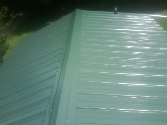 New green metal panels meeting at the ridge of a roof — Flat Roof Repair work by our crew in Mary D
