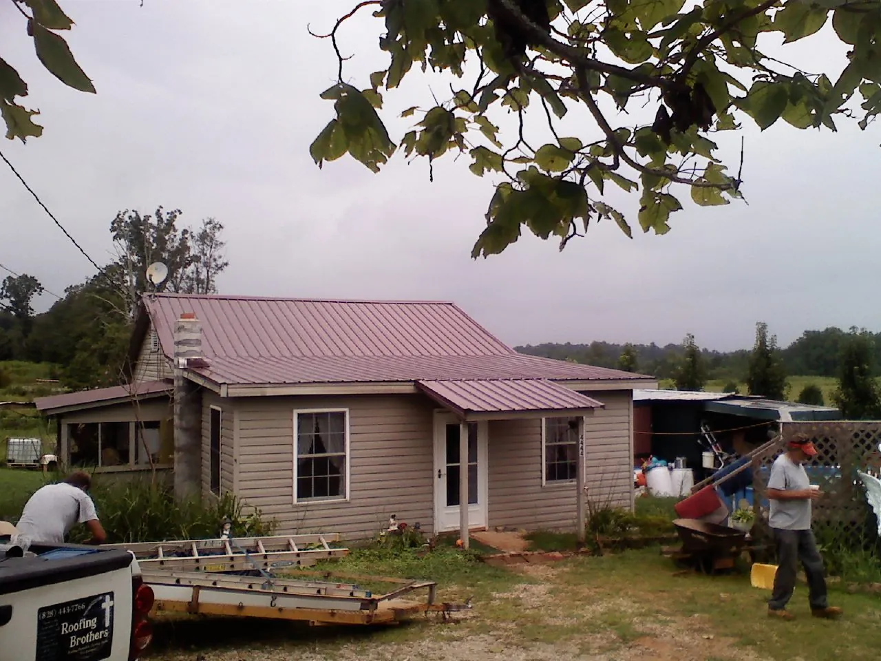Crew finishing a mauve metal roof on a small farmhouse in Mary D
