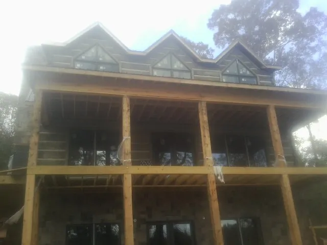 Dormers and porch framing on a large log home under construction — Roof Coating work by our crew in Mary D