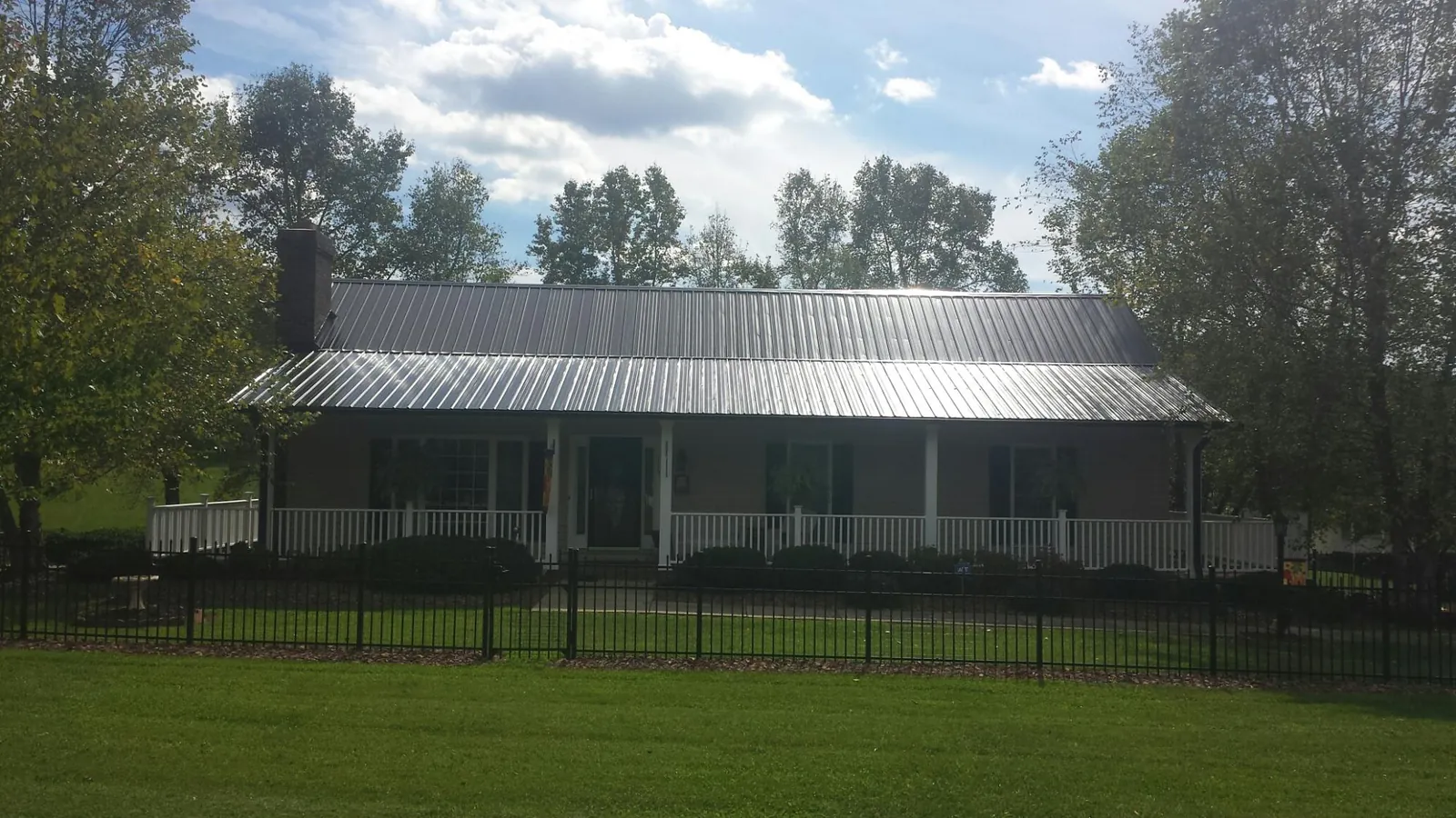 Gray metal roof on a brick ranch with a full width front porch — Gutter Guard Installation work by our crew in Mary D