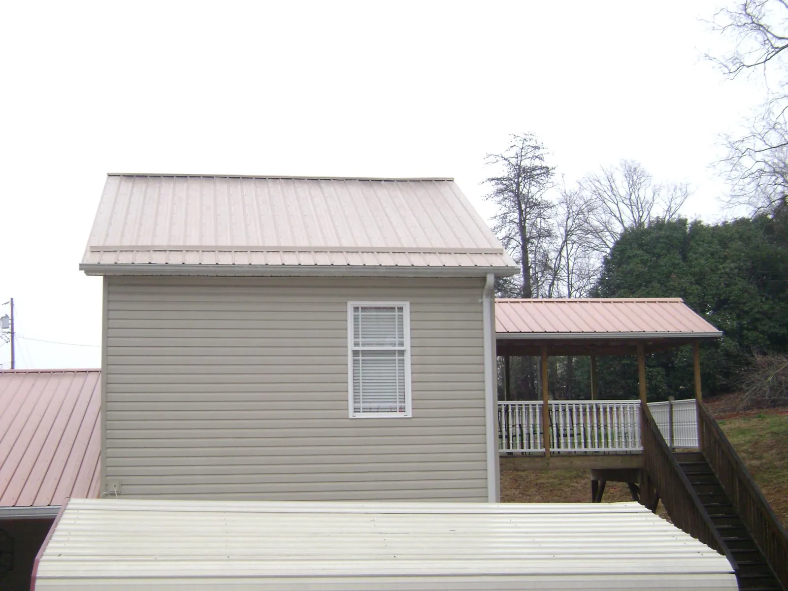 Tan metal roofs on a two story addition and attached porch, from a Roof Replacement job in Mary D
