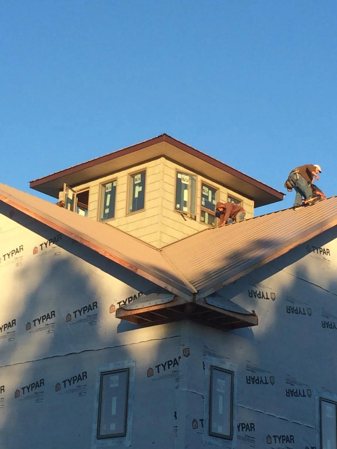 Roofers working around a rooftop cupola on a new metal roof at sunset — Roof Waterproofing in Mary D by Roofing Brothers